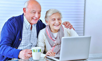 senior couple are laughing while looking at the laptop devices