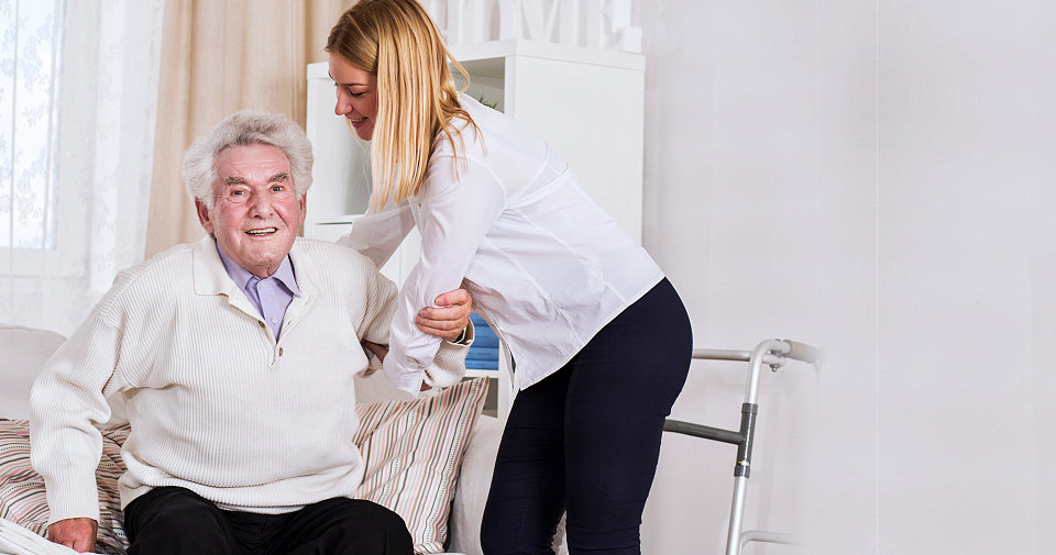 caregiver helping the smiling senior man