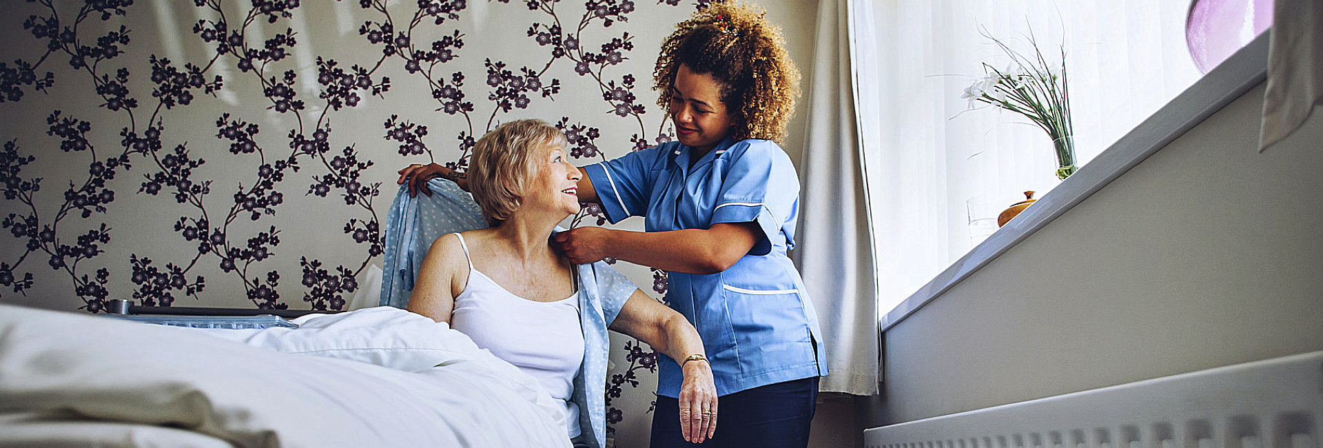 caregiver helping senior woman to wear a clothes
