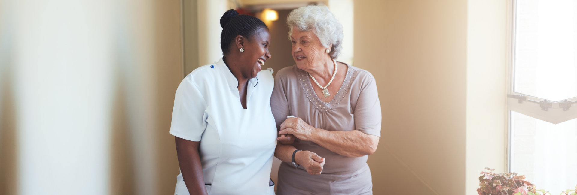 nurse and senior woman having a conversation while walking at the hallway