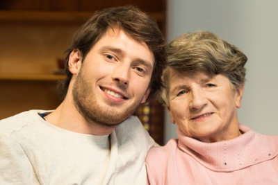 male caregiver and senior woman are smiling